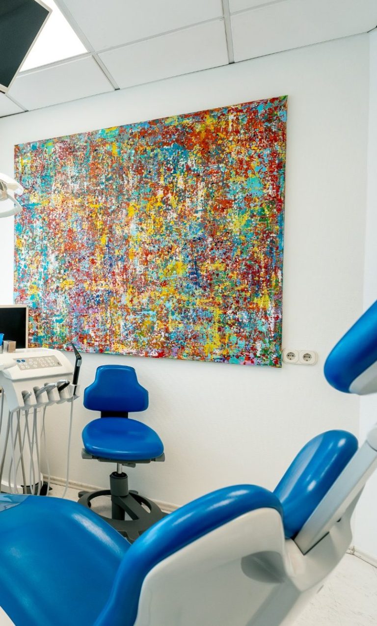 Bunte Wandkunst in einem modernen Zahnarztpraxisraum mit blauen Stühlen.